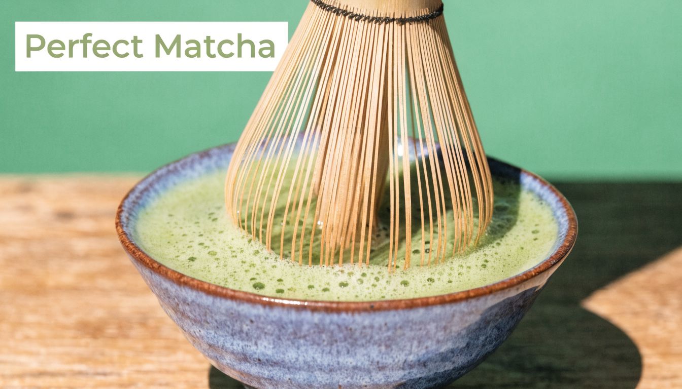 A bamboo matcha whisk frothing a bowl of vibrant green matcha tea on a wooden surface.