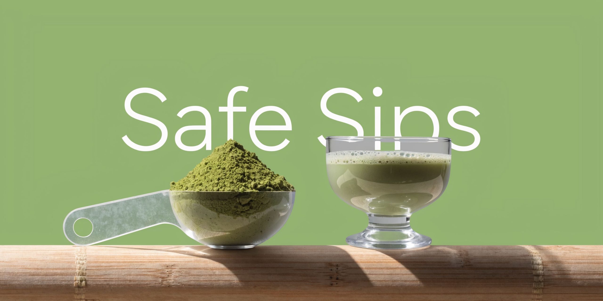 A scoop of green matcha powder next to a small glass of prepared matcha tea on bamboo.