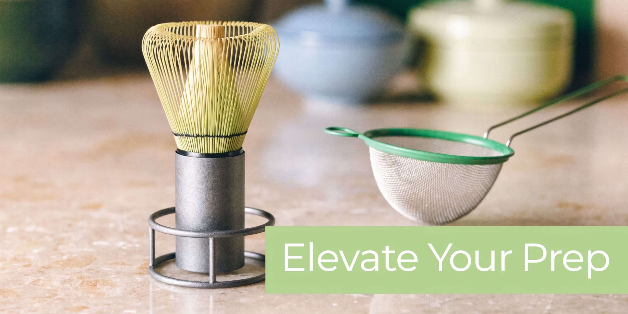 A bamboo matcha whisk on a stand next to a fine mesh strainer on a counter