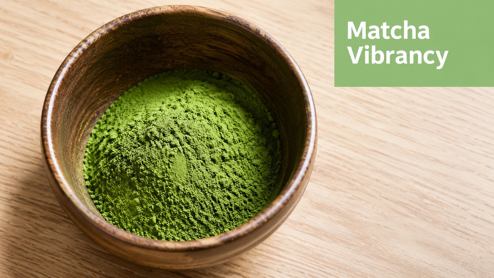 A wooden bowl filled with vibrant green matcha powder placed on a light wooden table surface.