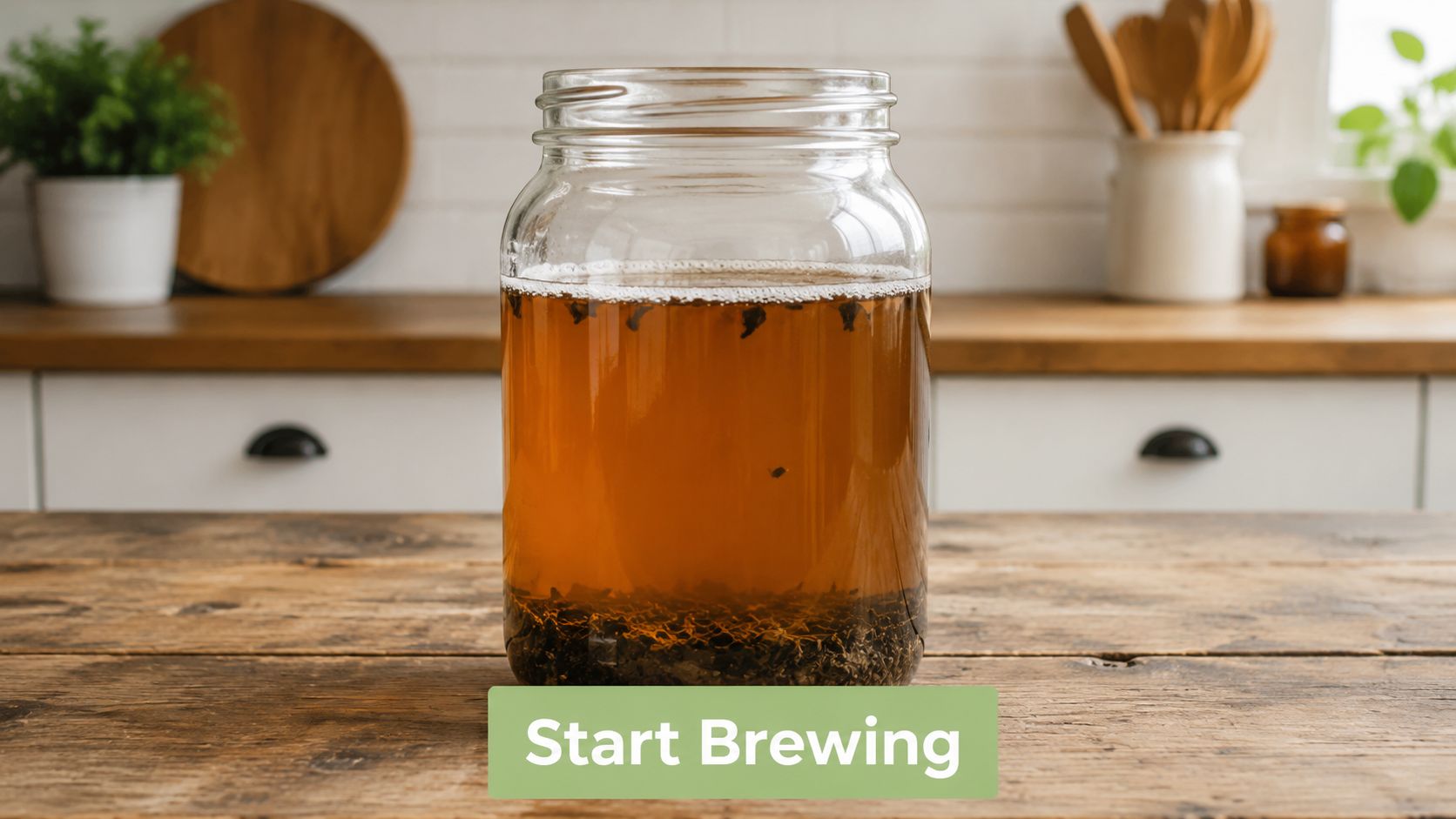 A glass jar filled with tea and tea leaves sits on a rustic wooden kitchen table.