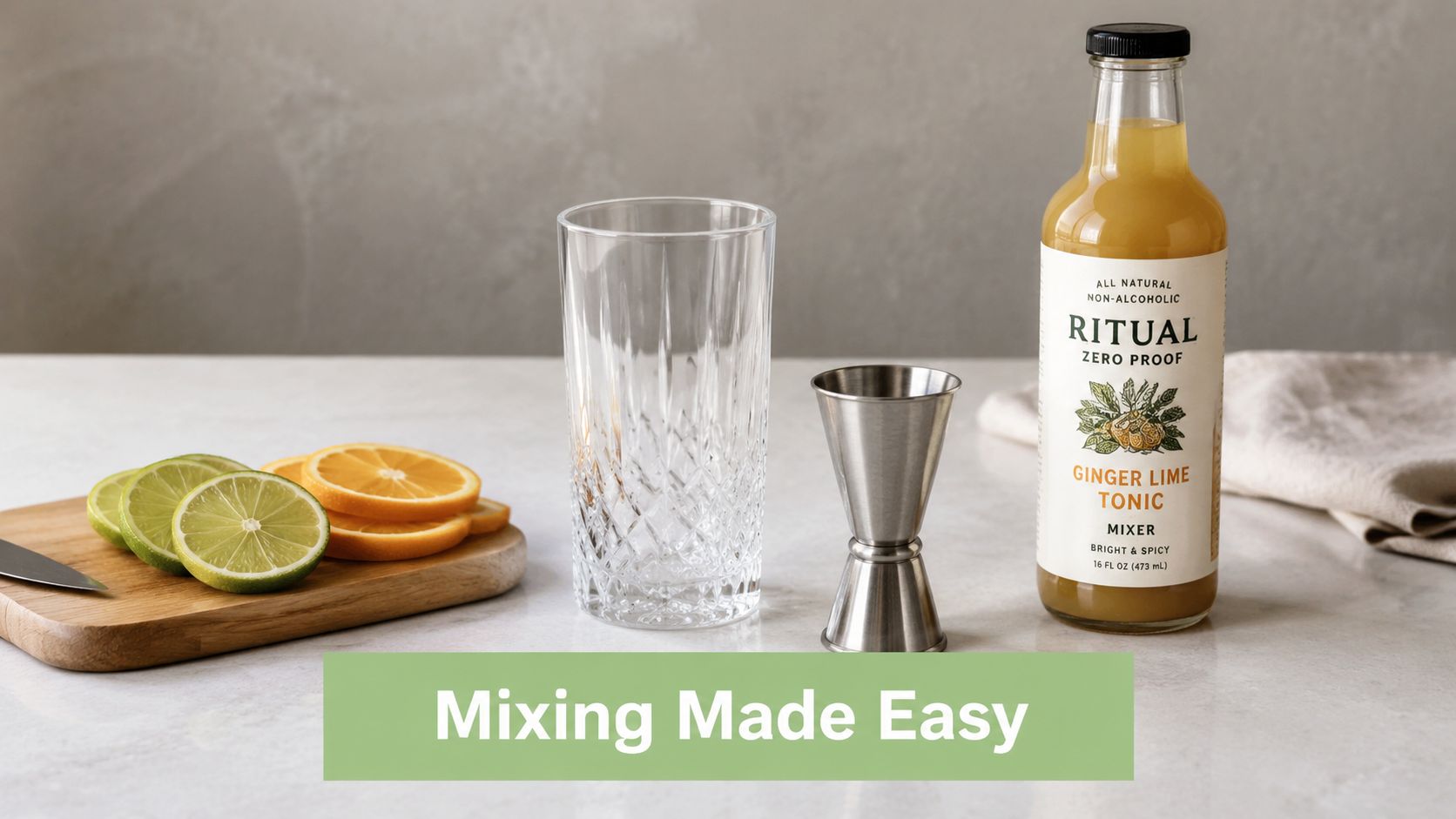 A glass, a jigger, lime slices, and a bottle of Ritual Zero Proof ginger lime tonic mixer.