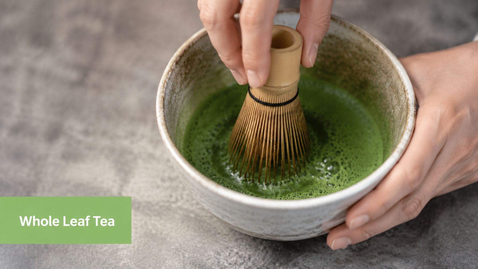 A close-up view of hands using a bamboo whisk to prepare vibrant green matcha tea in a bowl.
