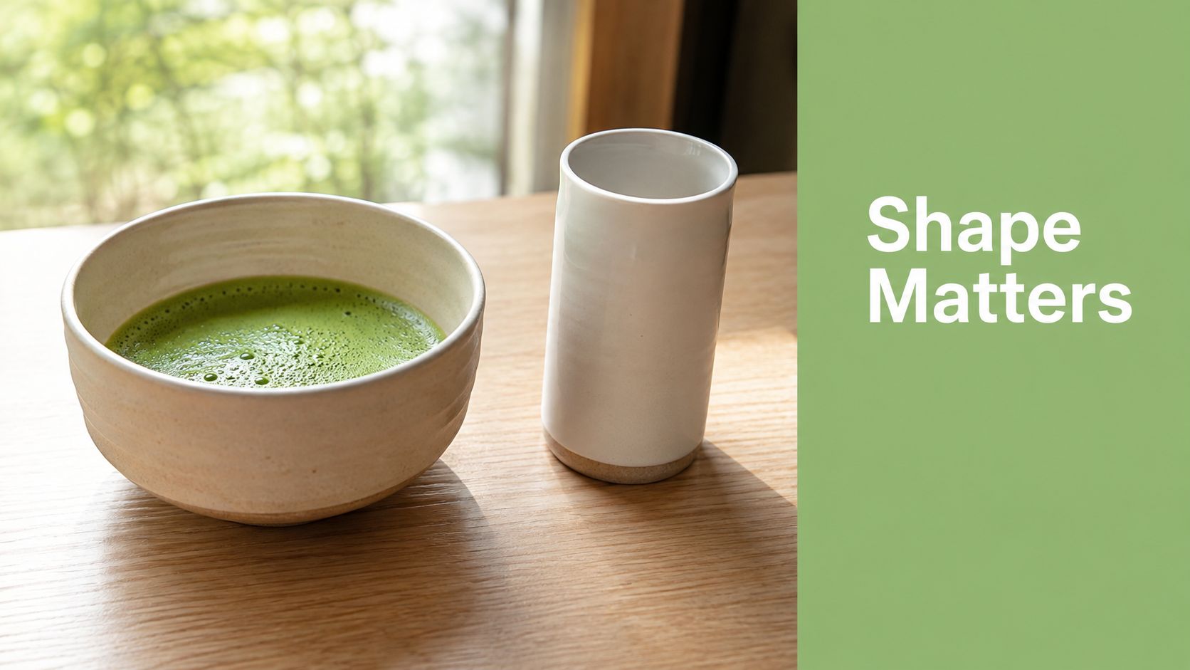 A ceramic matcha bowl and a tall white cup sit on a wooden table near a window.
