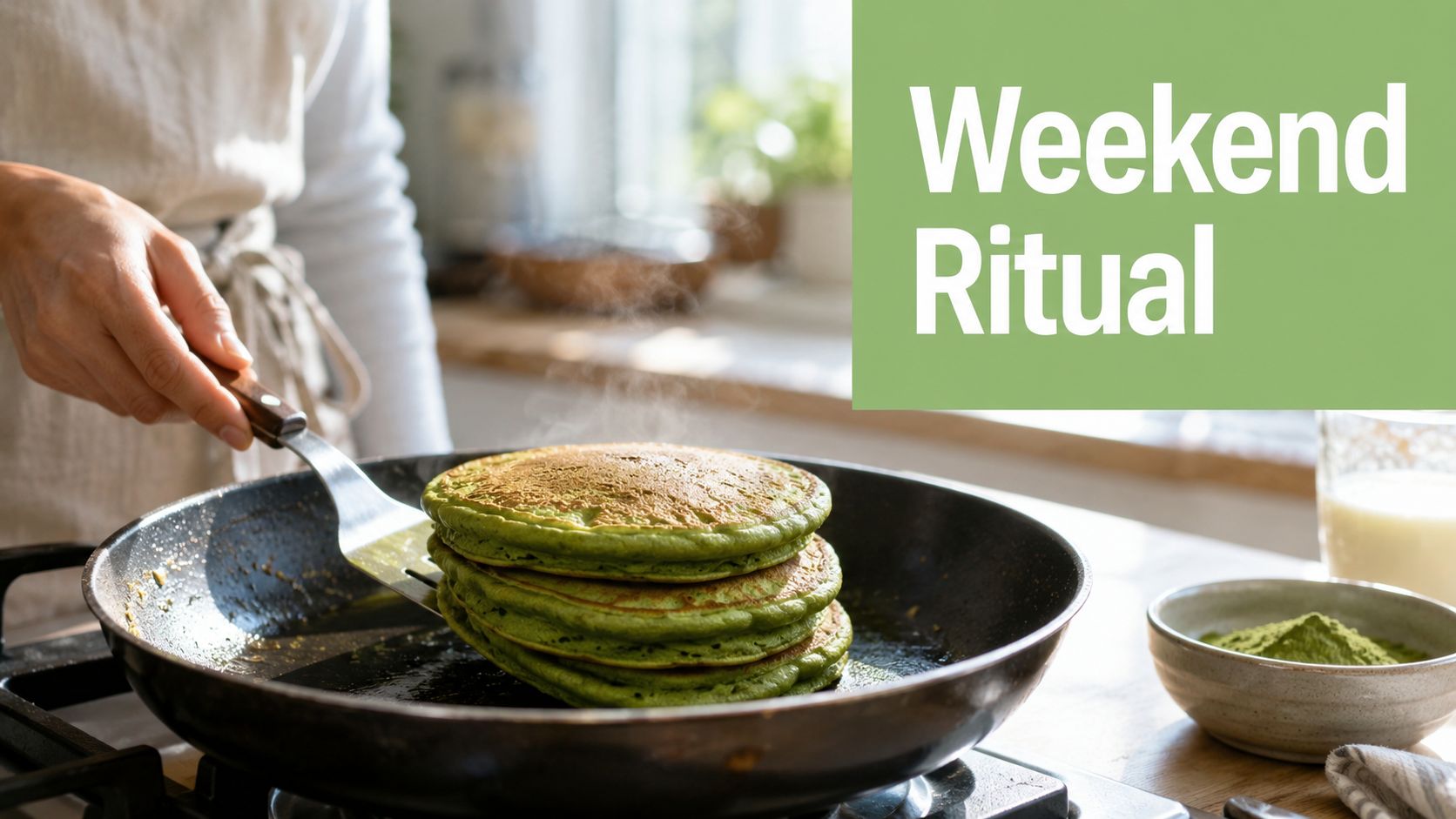 A person using a spatula to flip a stack of vibrant green matcha pancakes in a kitchen.