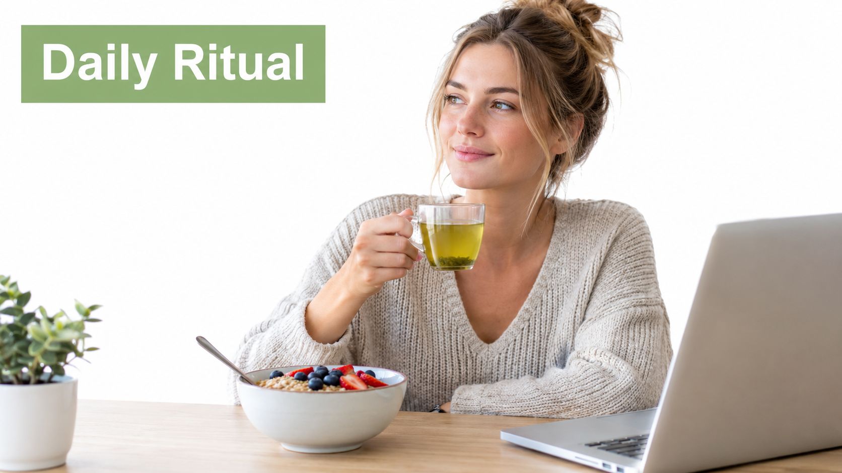 A woman sits at a desk with a laptop, enjoying a healthy bowl of fruit and green tea.