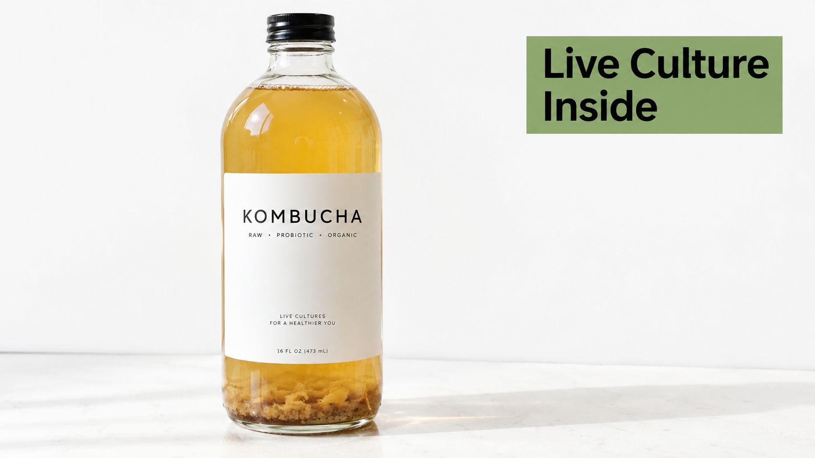A glass bottle of raw, organic kombucha sitting on a white surface with visible live cultures inside.