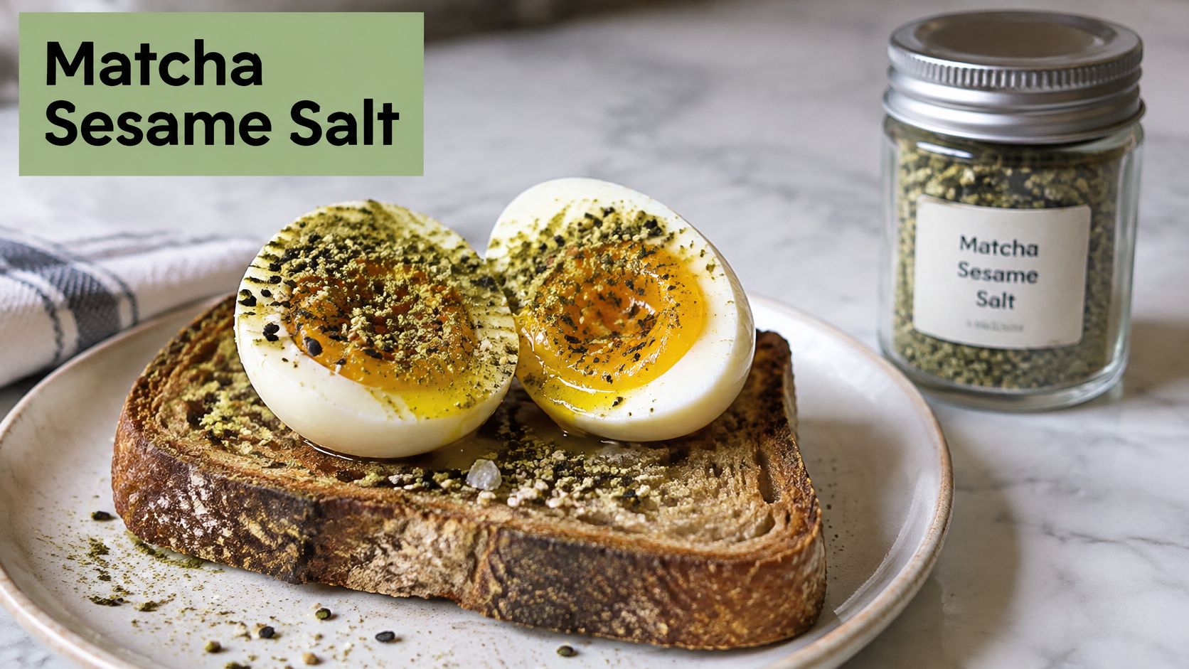 A halved soft-boiled egg topped with green matcha sesame salt, served on a slice of toasted sourdough bread.