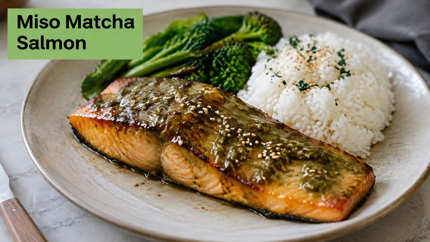A plate featuring a miso matcha glazed salmon fillet served with steamed white rice and fresh broccoli.